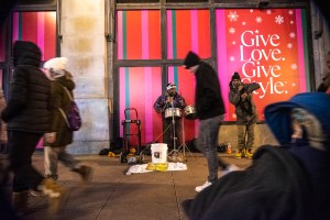 Chicago musician Kaliq Woods plays timbales on the sidewalk near State and Randolph streets as people walk by and one person dances next to him